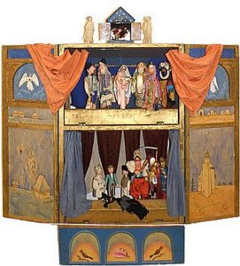 A large, rectangular, painted, wooden box is opened to reveal a puppet show stage, split into two halves. The top half contains puppets of angels and biblical figures. The bottom half contains many different types of puppets, which are the recurring characters of vertep theater.